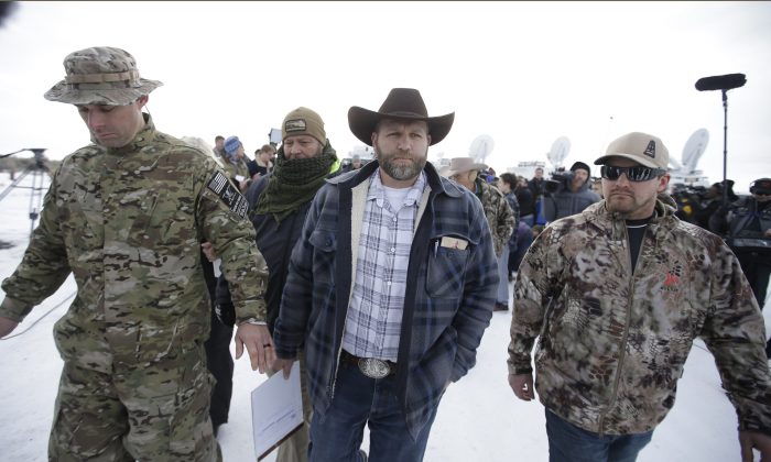 Ammon Bundy, center, one of the sons of Nevada rancher Cliven Bundy, walks off after speaking with reporters during a news conference at Malheur National Wildlife Refuge headquarters Monday, Jan. 4, 2016, near Burns, Ore. (AP Photo/Rick Bowmer)