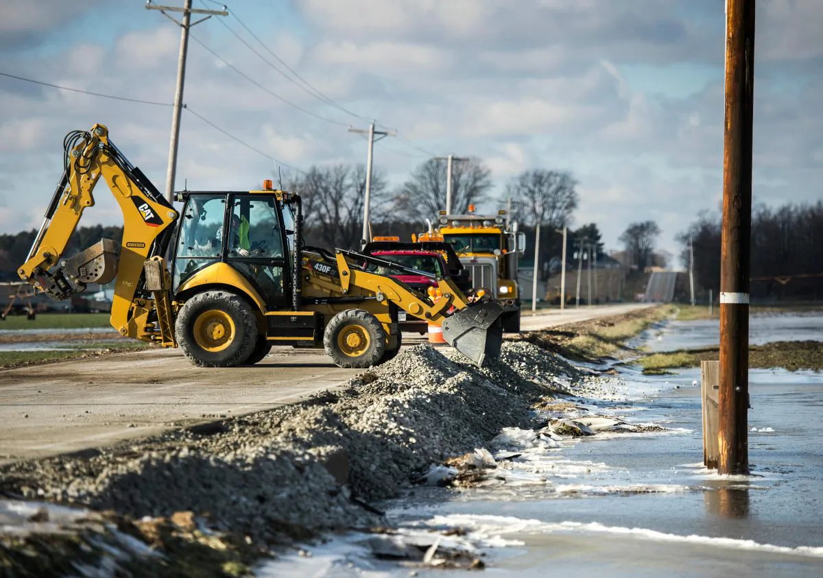 Tazewell County Highway Department work crews add gravel to rebuild the shoulder of Townline Road as floodwater from the Mackinaw River start to recede in Illinois on Jan. 4, 2016. (Fred Zwicky/Journal Star via AP)