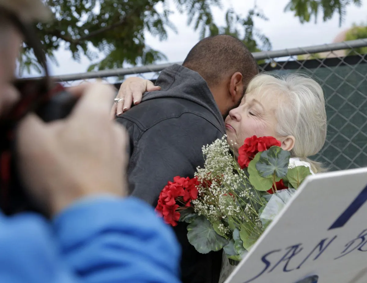 A photographer takes pictures of unidentified staff members as they hug before returning to work at the Inland Regional Center in San Bernardino, Calif., on Jan. 4, 2016, where an attack killed 14 people on the center’s campus on Dec. 2. (AP Photo/Nick Ut)