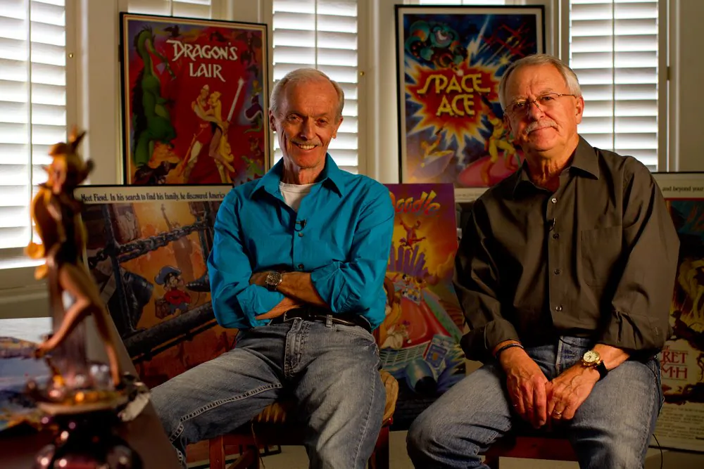 Filmmakers Don Bluth (L) and Gary Goldman (R) sit in front of posters of some of their works, including the games "Dragon's Lair" and "Space Ace," and the films "An American Tail" and "Rock-a-Doodle." The two are now hoping to rekindle traditional animation with their upcoming film, "Dragon's Lair." (Don Bluth Animation)