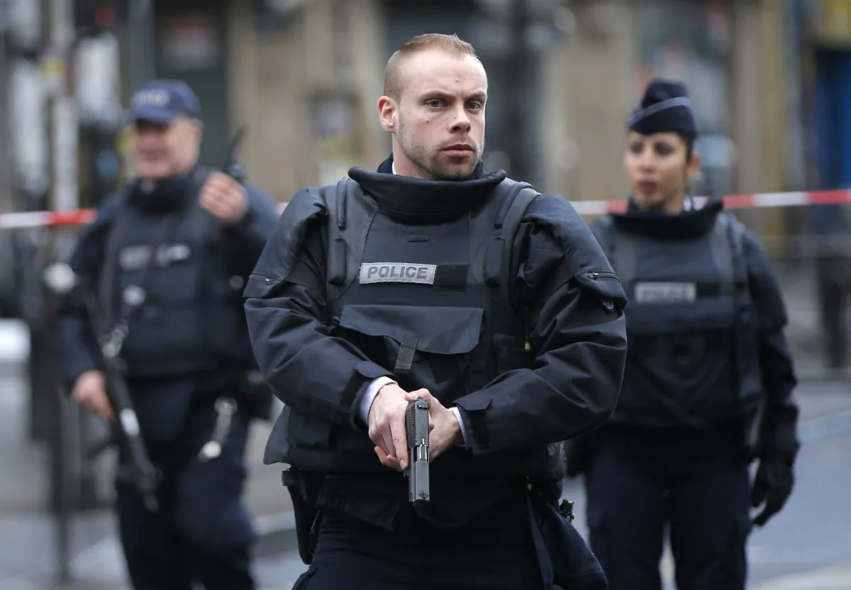 Police officers secure the perimeter near the scene of a fatal shooting which took place at a police station in Paris on Jan. 7, 2016. (AP Photo/Christophe Ena)