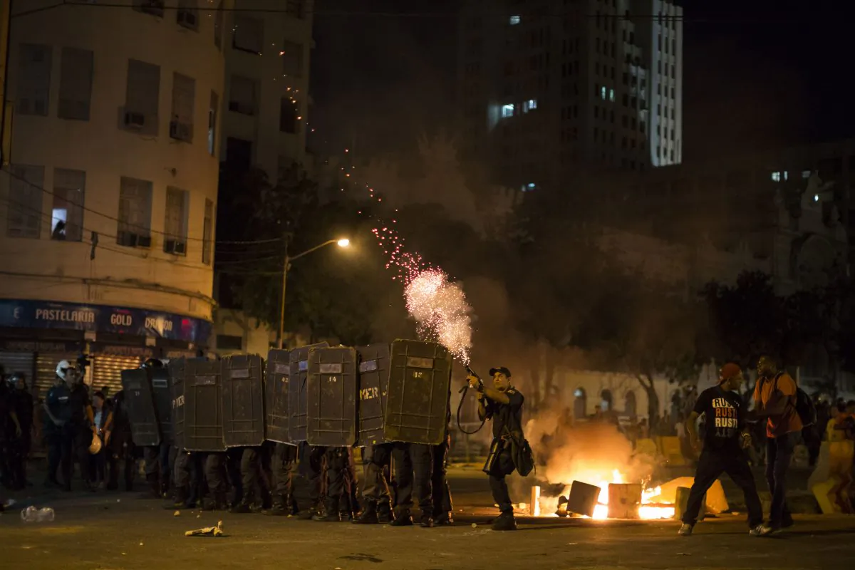 A police officer fires tear gas toward protesters during a march against bus fare hikes in Rio de Janeiro, Brazil, on Jan. 8, 2016. The march, which is also taking place in other Brazilian capitals, began peacefully in downtown Rio de Janeiro but turned violent. (AP Photo/Felipe Dana)