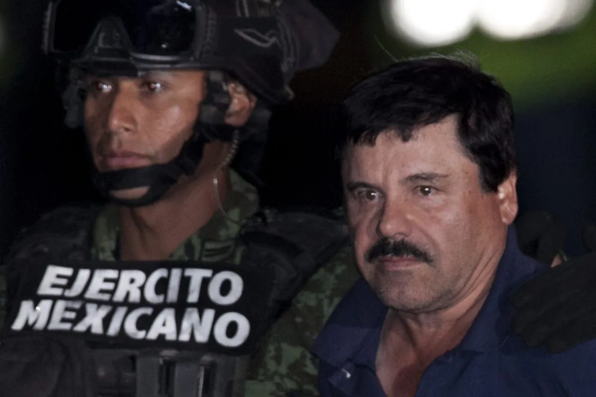 Mexican drug lord Joaquin "El Chapo" Guzman (R) is escorted by soldiers and marines to a waiting helicopter, at a federal hangar in Mexico City on Jan. 8, 2016. (AP Photo/Marco Ugarte)