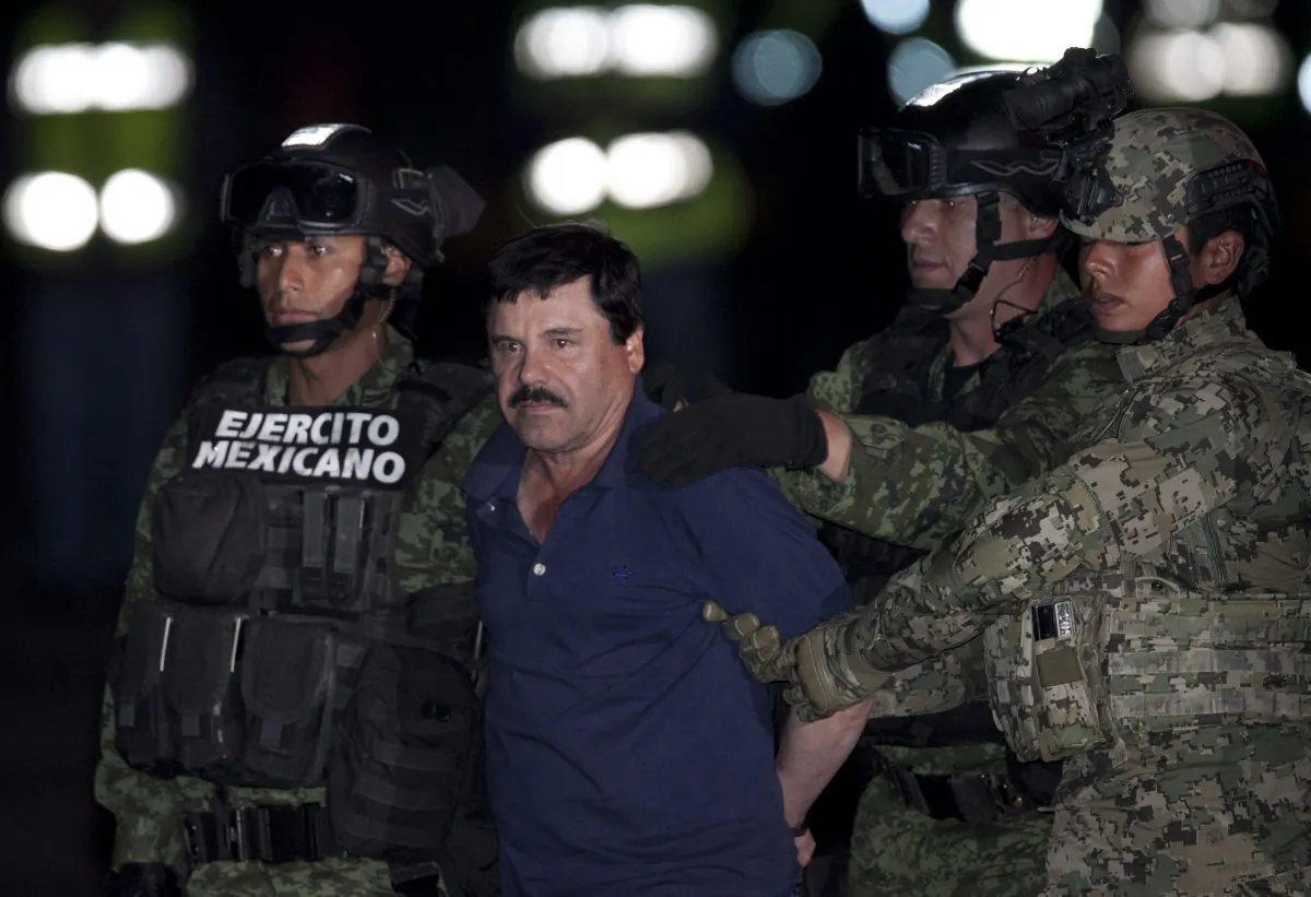 Mexican drug lord Joaquin "El Chapo" Guzman is escorted by army soldiers to a waiting helicopter, at a federal hangar in Mexico City, Friday, Jan. 8, 2016. The world's most wanted drug lord was recaptured by Mexican marines Friday, six months after he fled through a tunnel from a maximum secuirty prison in a made-for-Hollywood escape that deeply embarrassed the government and strained ties with the United States. (AP Photo/Marco Ugarter)
