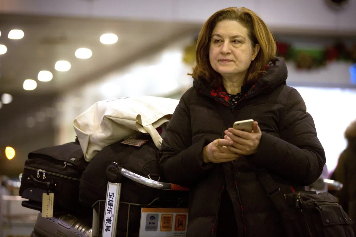 French journalist Ursula Gauthier, a reporter in China for the French news magazine L'Obs, checks her cellphone as she waits at Bejing Capital International Airport in Beijing on Dec. 31, 2015. (AP Photo/Mark Schiefelbein)
