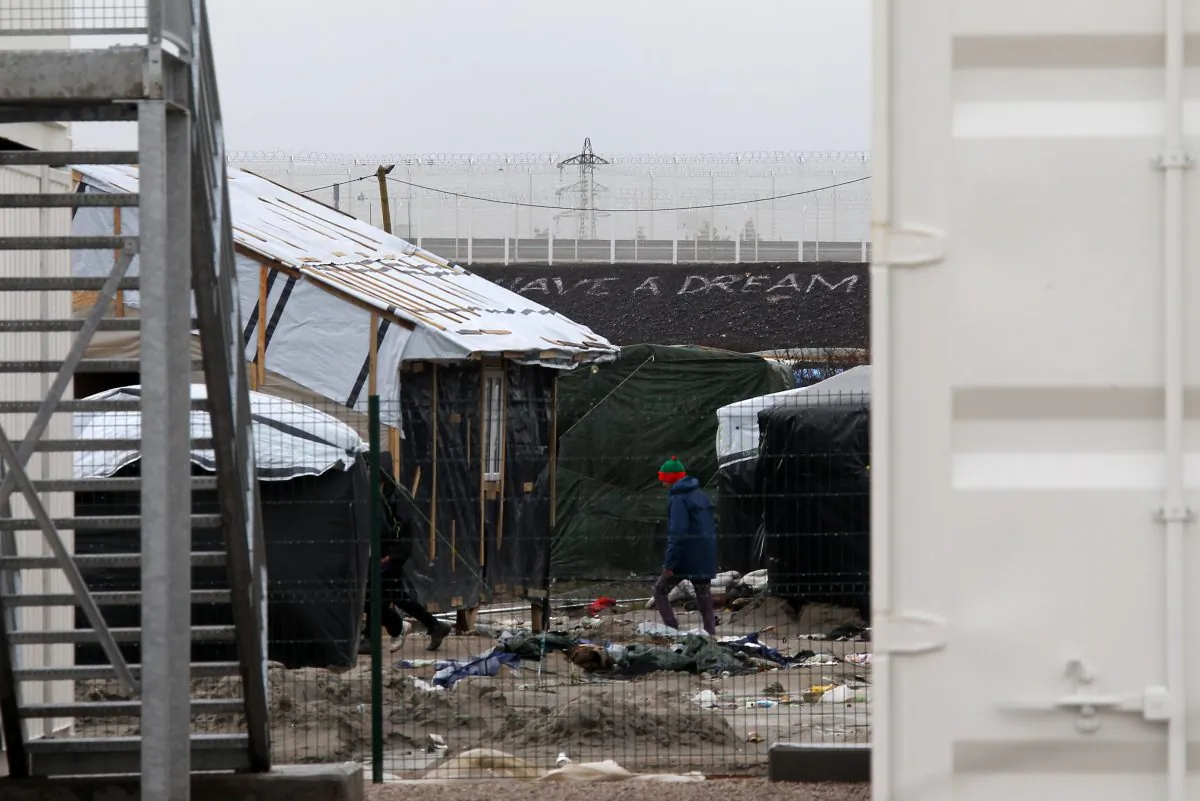 A migrant walks at the entrance of the Calais refugee camp in Calais, northern France, on Jan. 11, 2016. Approximately 130 containers will be converted to shelters to accommodate as many as 1,500 migrants who are expected to move in on Monday. (AP Photo/Michel Spingler)