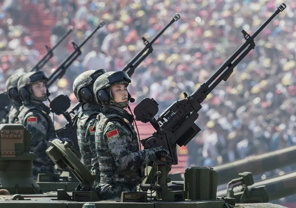 Chinese soldiers ride in an armoured vehicle as they hold machine guns while passing in front of Tiananmen Square and the Forbidden City during a military parade on September 3, 2015 in Beijing, China. (Kevin Frayer/Getty Images)