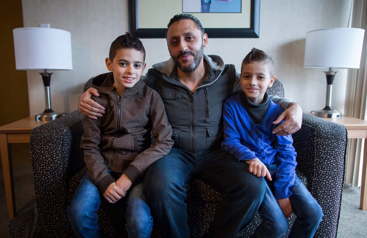 Newly arrived Syrian refugees Ahmad Hwichan and his sons Louai and Qusai pose for a photograph at a hotel where they're living temporarily in Vancouver on Jan. 12, 2016. (THE CANADIAN PRESS/Darryl Dyck)