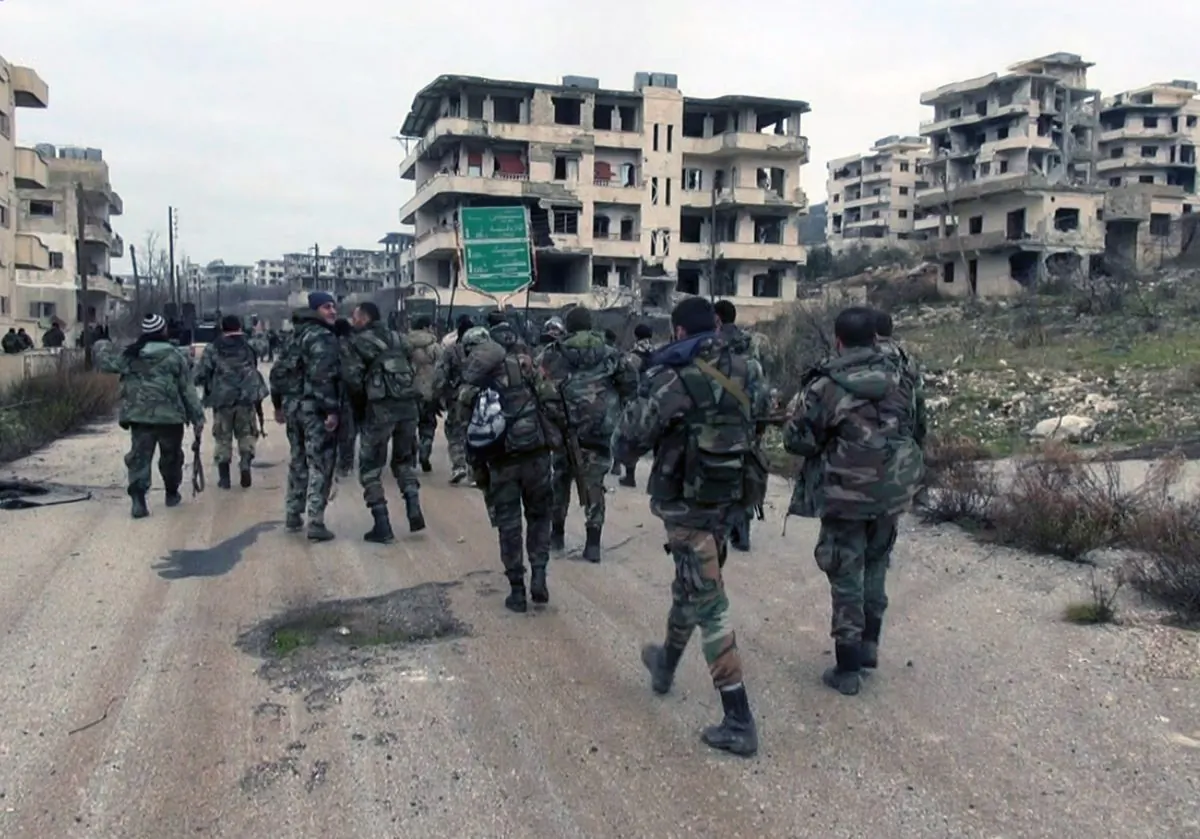 In this photo released on Tuesday, Jan 12, 2016, by the Syrian official news agency SANA, shows Syrian government troops and allied militiamen walk inside the key town of Salma in Latakia province, Syria. (SANA via AP)