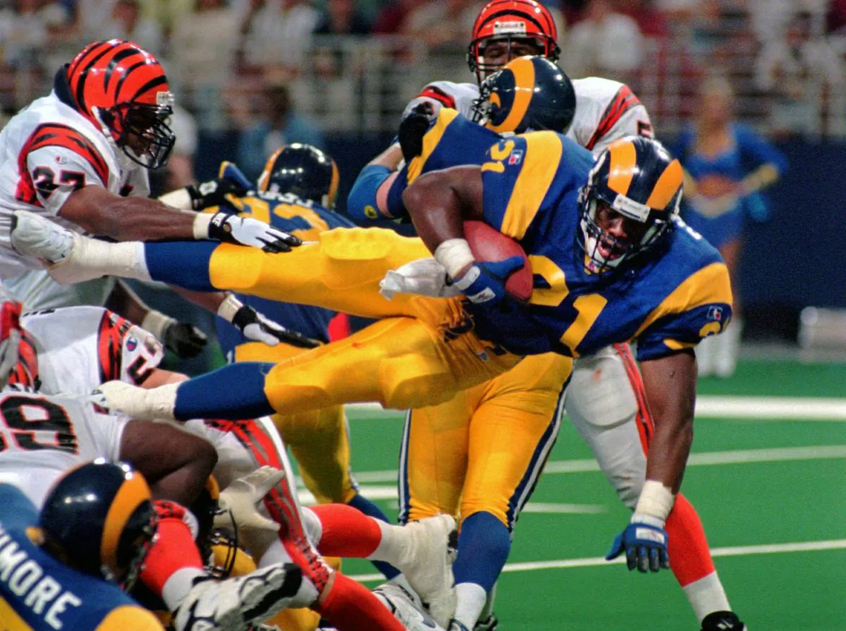 This Sunday, Sept. 1, 1996, file photo shows St. Louis Rams running back Lawrence Phillips (21) leaping over a mound of players as he scores against the Cincinnati Bengals in St. Louis, Mo. Former NFL running back, Phillips was found dead in his California prison cell early Wednesday, Jan. 13, 2016, and officials said they suspect suicide. (AP Photo/L.G. Patterson, File)