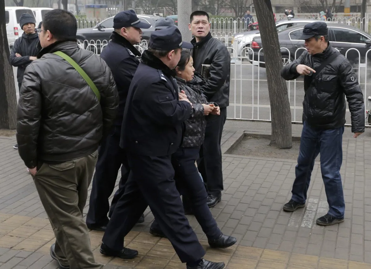 Police officers take away a supporter of rights lawyer Pu Zhiqiang near the Beijing Second Intermediate People's Court during Pu's trial in Beijing, Monday, Dec. 14, 2015. (AP Photo/Andy Wong)
