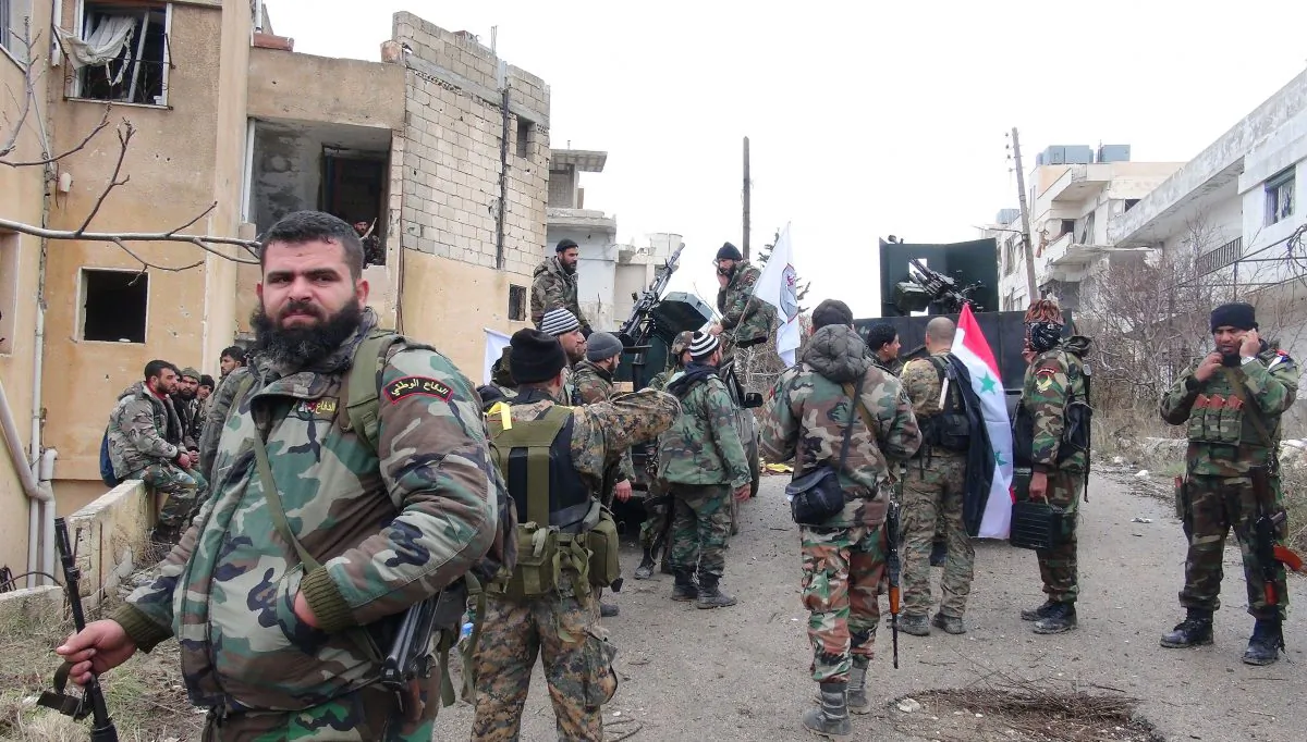 Forces loyal to the Syrian regime stand on a street with national flags after Syria's army and allied forces took full control from rebel groups of the strategic town of Salma, in the northwestern province of Latakia on Jan. 12. (Stringer/AFP/Getty Images)