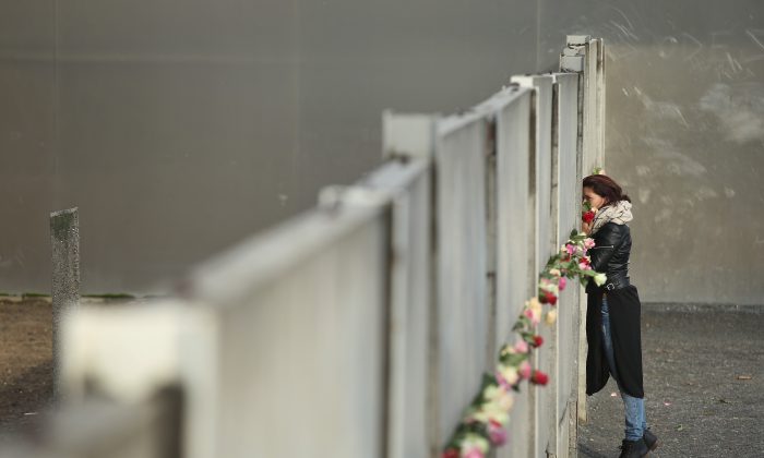 A woman places flowers at the remains of the Berlin Wall on Nov. 9, 2015, the 26th anniversary of its demolition. From 1961 to 1989, the Wall, built to keep East Germans from emigrating to the democratic west, was a symbol of the Cold War and Soviet communism. (Sean Gallup/Getty Images)