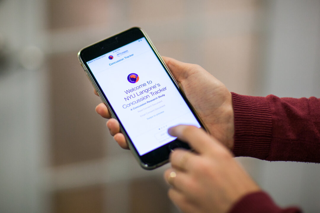A woman uses the Concussion Tracker app on her iPhone in New York on Jan. 14, 2016. (Benjamin Chasteen/Epoch Times)