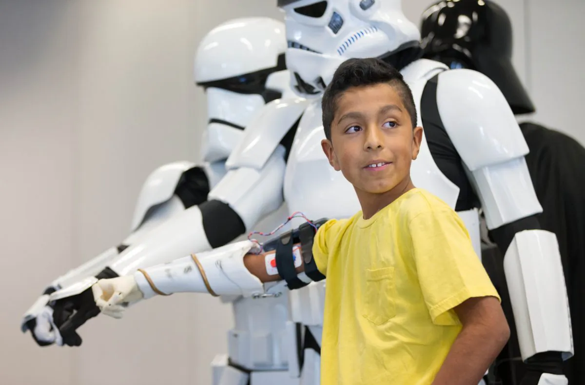 In this Thursday, Jan. 14, 2016, photo, Alvin Garcia Flores poses for photos with Storm Troopers as he shows off his new bionic arm in Omaha, Neb. Garcia Flores, a 4th-grade student at Gateway Elementary School in Omaha, received a 3D-printed bionic arm from Limbitless Solutions, which was delivered by volunteers from the 501st Legion, the national fan organization for Star Wars. (Matt Miller/The World-Herald via AP) 