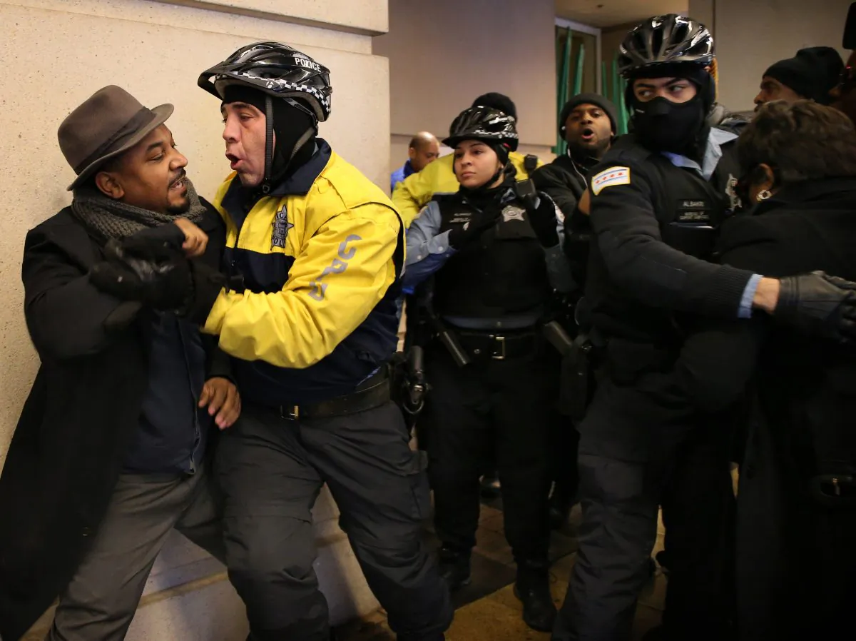 Willie Preston, left, scuffles with a police officer after he and other protesters tried to keep two women, partly seen at right, from attending the annual Interfaith Breakfast at the Hyatt Regency McCormick Place hotel in Chicago, Friday, Jan. 15, 2016. (Antonio Perez/Chicago Tribune via AP) 
