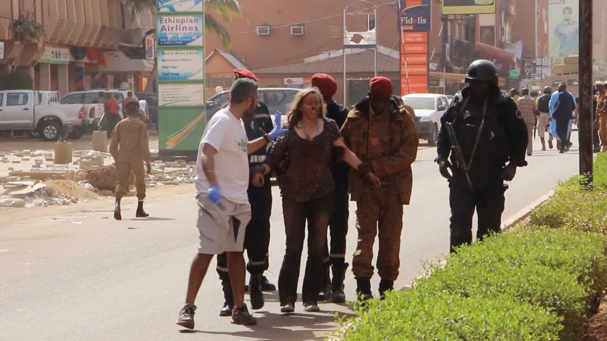 This image taken from AP television shows a woman being led to safety in Ouagadougou, Burkina Faso, on Jan. 16, 2016. (AP Photo)