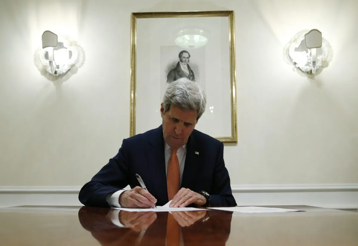 Secretary of State John Kerry signs a series of documents in Vienna, Austria, on Jan. 16, 2016. Kerry confirms Iran in compliance with nuclear deal and lifts U.S. nuclear-related sanctions. (Kevin Lamarque/AP)