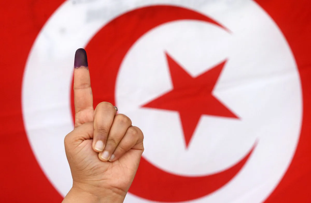 A Tunisian woman raises her ink-stained finger in front of a national flag after casting her vote in the country's first post-revolution presidential election on Nov. 23, 2014, at a polling station in the capital Tunis. (Fadel Senna/AFP/Getty Images)