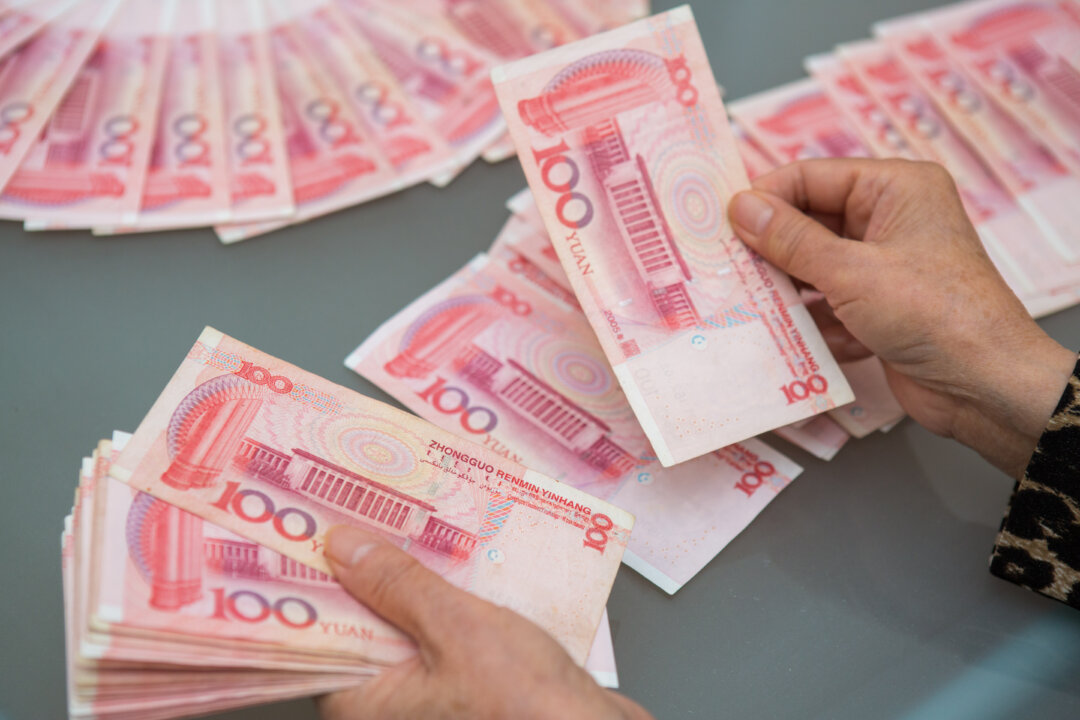A woman counts Chinese yuan bills worth thousands of dollars in Vancouver, Canada, on Oct. 27, 2015. (Benjamin Chasteen/The Epoch Times)