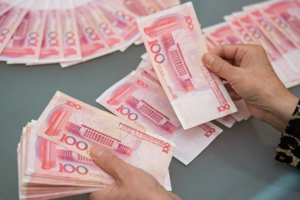 A woman counts Chinese yuan bills worth thousands of dollars in Vancouver, Canada, on Oct. 27, 2015. (Benjamin Chasteen/The Epoch Times)