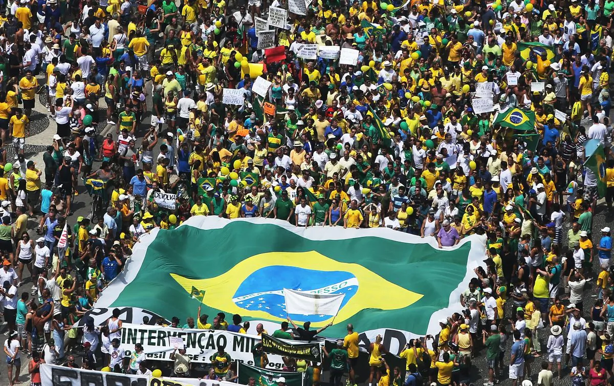 Anti-government protesters march carrying a Brazilian flag along Copacabana beach in Rio de Janeiro, Brazil, on March 15, 2015. Millions protested across the country against President Dilma Rousseff's government and the ruling Workers' Party, with many calling for Rousseff's impeachment. A massive corruption scandal at Brazil's state-owned oil company Petrobras has rocked the government and Dilma's approval ratings—now below 8 percent. Brazil's inflation rate has hovered around ten-year highs recently while the currency, the Brazilian real, has passed twelve-year lows when measured against the U.S. dollar. (Mario Tama/Getty Images)