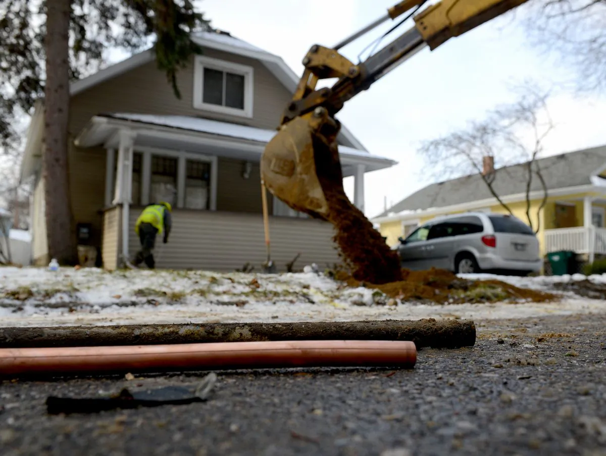 As the hole is filled in in the background, a piece of an old lead water pipe sits next to a new copper pipe at a home on Greencroft in Lansing, Mich., on Jan. 22, 2016. (Dave Wasinger/Lansing State Journal via AP)