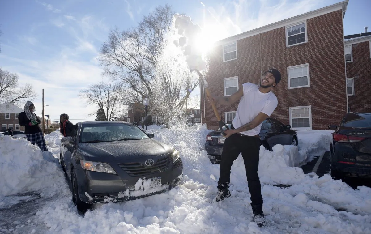 Mike Roach, right, of New York, a junior at Towson University, clears snow from his car after getting stuck in Towson, Md., Monday, Jan. 25, 2016. (AP Photo/Steve Ruark)