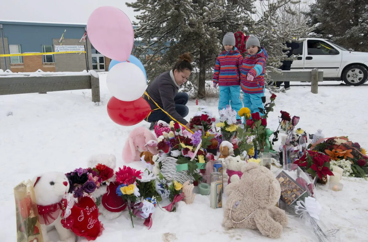 Tashina Montgrand lays flowers outside the La Loche Community School as her daughters look on, Jan. 25, 2016. The Saskatchewan community is struggling to recover after a shooting that left four dead and seven wounded. THE CANADIAN PRESS/Jonathan Hayward