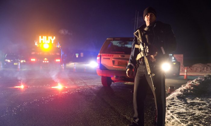Sgt. Tom Hutchison stands in front of an Oregon State Police roadblock on Highway 395 on Tuesday, Jan. 26, 2016 between John Day and Burns, Ore.  The FBI on Tuesday arrested the leaders of an armed group that has occupied a federal wildlife refuge in eastern Oregon for the past three weeks.  (Dave Killen/The Oregonian via AP) 