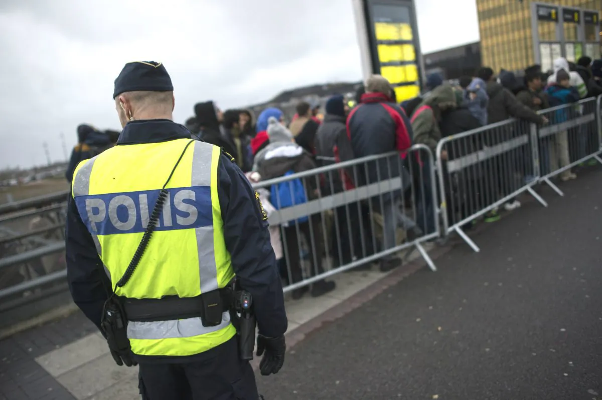 A policeman watches over a queue of newly arrived people at Hyllie Station, outside Malmo, Sweden, on Nov. 19, 2015. (Johan Nilsson/TT News Agency via AP)