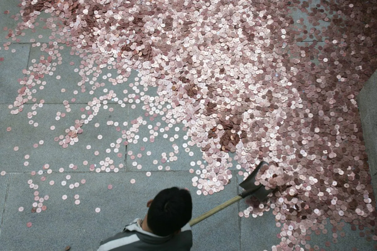 A worker gathers coins thrown by tourists into a well to pray for good luck and wealth during celebration for Chinese New Year at White Cloud Temple in Beijing on Feb. 18, 2007. China's foreign exchange reserves are disappearing as fast as the coins. (China Photos/Getty Images)
