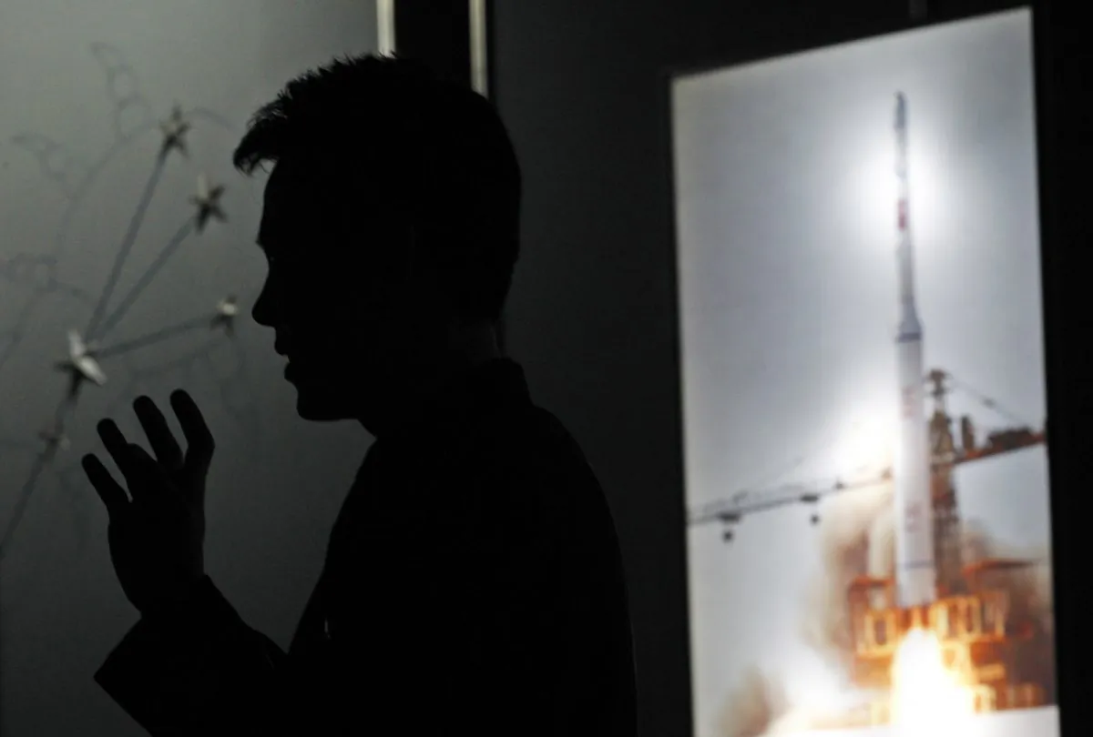 North Korean guide Kim Won Ho speaks near a photo depicting the 2009 satellite rocket launch at the Three Revolutions exhibition hall in Pyongyang, North Korea, on April 10, 2012. (AP Photo/Ng Han Guan)