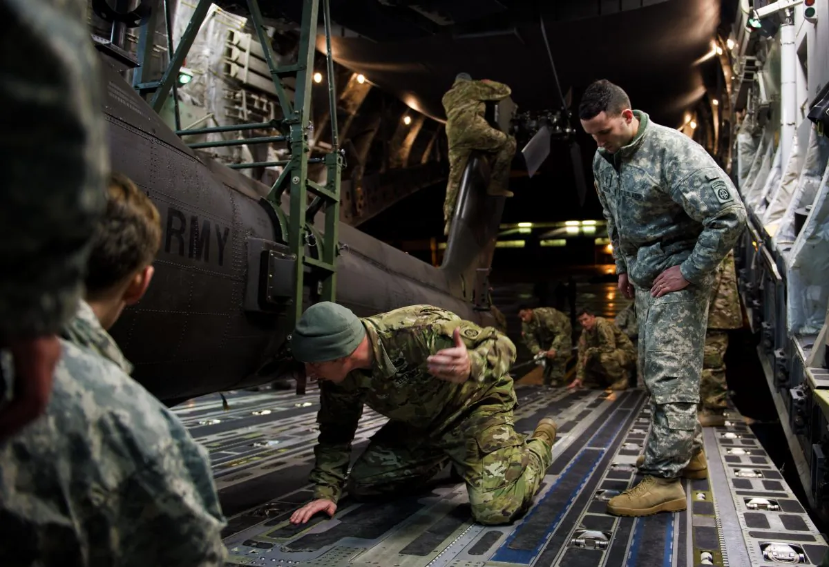 Soldiers and airmen work together to secure an AH-64 Apache helicopter onboard a C-17 Globemaster III on Pope Army Airfield, N.C., on Feb. 4. The new defense budget will make military service more attractive as a career. (Staff Sgt. Paul Labbe/U.S. Air Force)