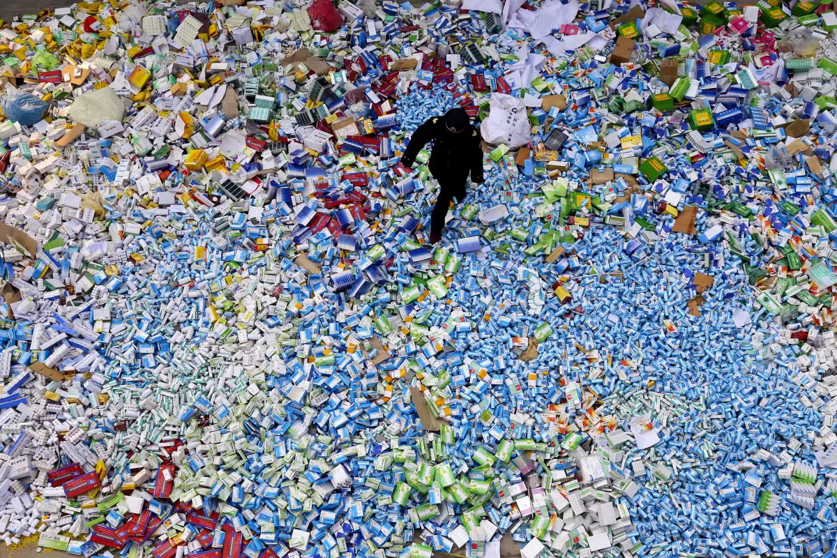 A Chinese policeman walks across a pile of fake medicines seized in Beijing on March 14, 2013. It is shame that Chinese buy up flu medicine in Japan, said a Party official. (STR/AFP/Getty Images)