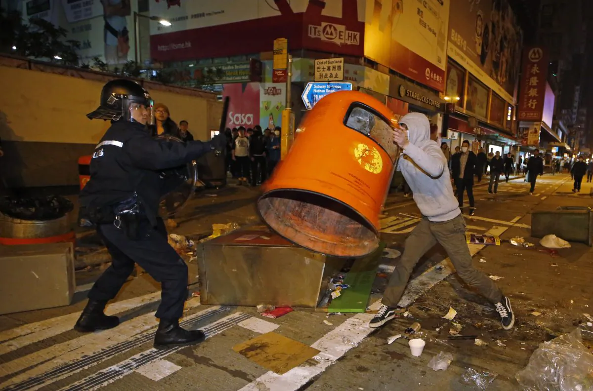 A rioter tries to throw a litter bin at police on a street in Mong Kok district of Hong Kong, Tuesday, Feb. 9, 2016. (AP Photo/Kin Cheung)