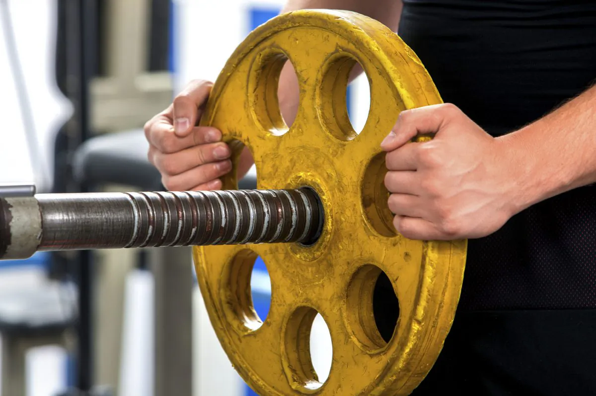 An undated file photograph of a person adding a weight to a barbell. (Targovcom/iStock)