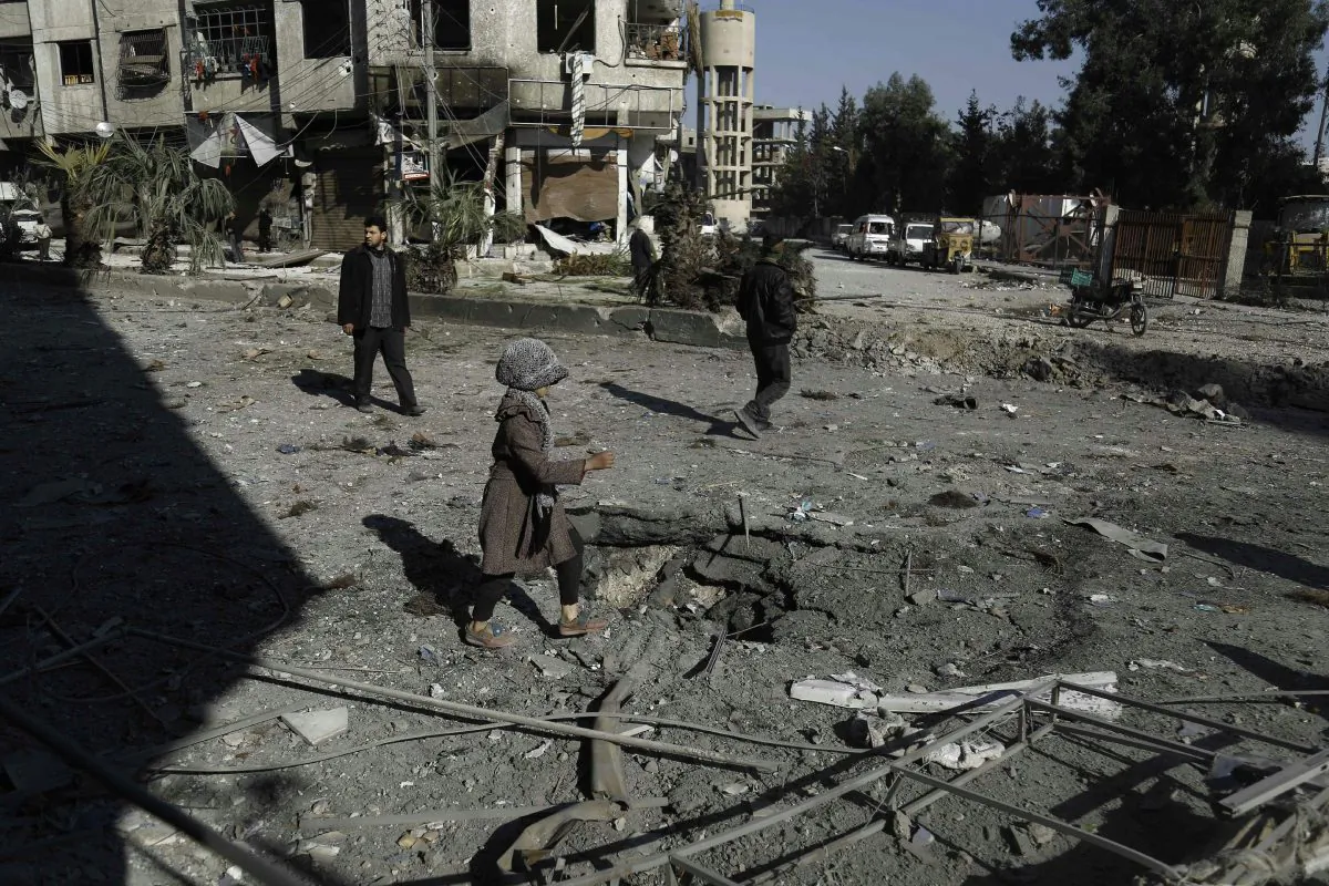 A Syrian girl makes her way through debris following reported air strikes in Hammuriyeh on the outskirts of the capital Damascus, on Feb. 12. The civil war in Syria is escalating ahead of a planned ceasefire. (Abdulmonam Eassa/AFP/Getty Images)