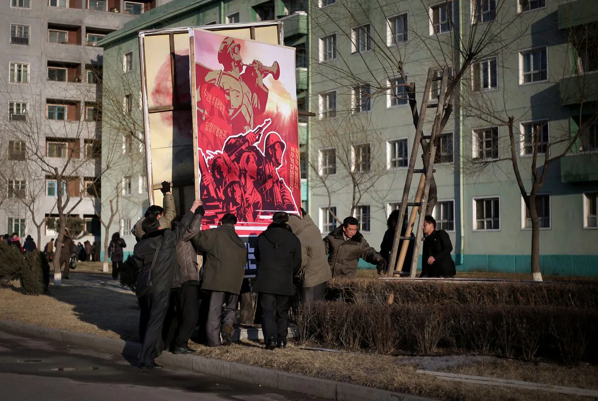 North Korean men put up a propaganda poster urging its citizens to carry out their country's ruling party's goals for North Korea with an unwavering spirit in Pyongyang, North Korea, on Feb. 14, 2016. (AP Photo/Wong Maye-e)