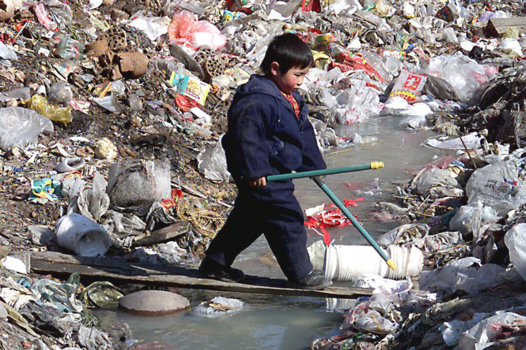 A young boy carefully walks on a thin board across a heavily polluted stream and  trash dump outside his family's old courtyard house in Beijing on Feb. 16, 2000. Experts at China Geological Survey, a state-led research institute, said at a conference in 2010 that 90% of China's underground water sources are polluted to one degree or another, while 60% are seriously polluted. (Stephen Shaver/AFP/Getty Images)