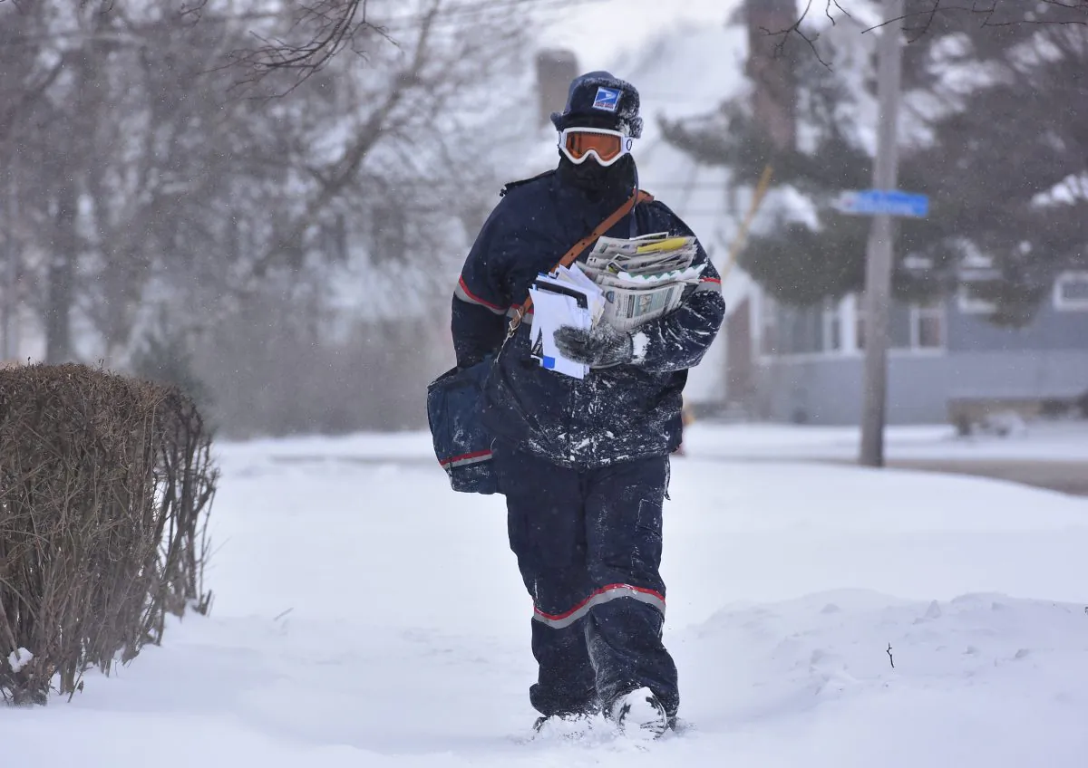 Jake Cote, a carrier with the United States Postal Service, delivers mail along Sunset Avenue, Thursday, Feb. 11, 2016, in Utica, N.Y.  (Mark DiOrio/Observer-Dispatch via AP)