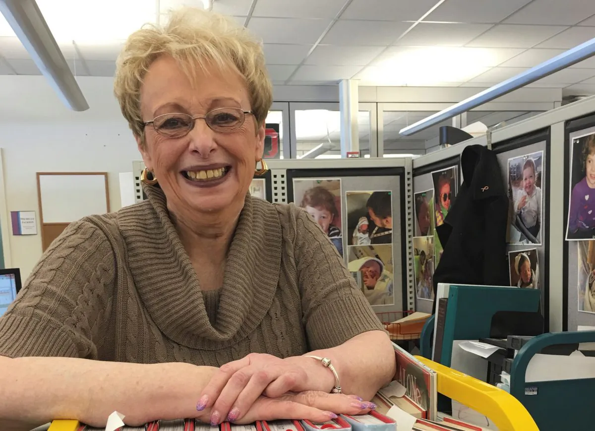 Carrie Ingle, 77, poses at her desk at the Columbus Metropolitan Library Operations Center in Columbus, Ohio, on Thursday, Feb. 18, 2016. Ingle has worked for the library for six decades. Sixty years have come and gone, and Ingle still is working full time behind the scenes, still surrounded each day by stacks of brand new books in what is now one of the busiest big-city library systems in the country. (AP Photo/Mitch Stacy)
