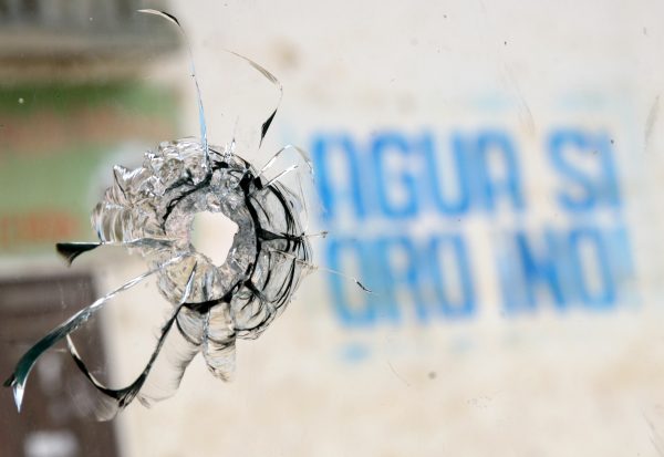 Sign reading "Water Yes, Fri No!  ," Seen through a window with a hole in the projectile after a clash between police and protesters of a conga mining project in the Andean town of Celendín in Cajamarca, Peru, on July 5, 2012. In Kahamalka, a total of five civilians were killed and more than 20 were injured after a two-day protest against the conga mining project. Meanwhile, police refused to use guns in crowd management activities in the area.  (STR / AFP / GettyImages)