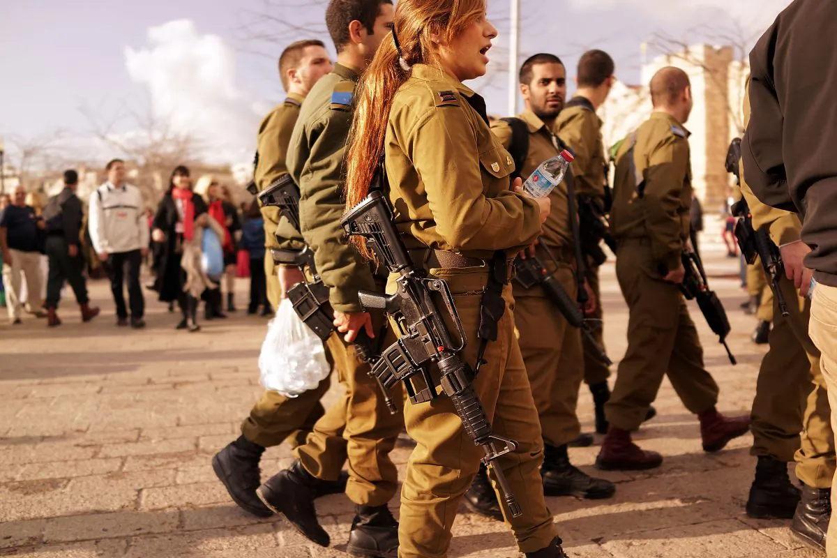 Young members of the Israeli Defense Forces (IDF) pause in a park near the Old City on Nov. 28, 2014, in Jerusalem, Israel. Soldiers with the IDF are now required to carry their firearms while off duty. (Spencer Platt/Getty Images)
