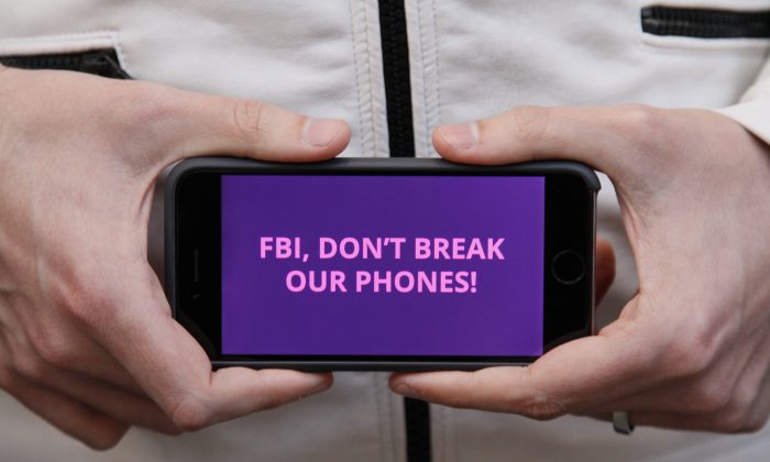 A man holds out his iPhone during a rally in support of data privacy outside the Apple store in San Francisco on Feb. 23, 2016. Protesters assembled in more than 30 cities to lash out at the FBI for obtaining a court order that requires Apple to make it easier to unlock an encrypted iPhone used by a gunman in December's mass murders in California. (AP Photo/Eric Risberg)