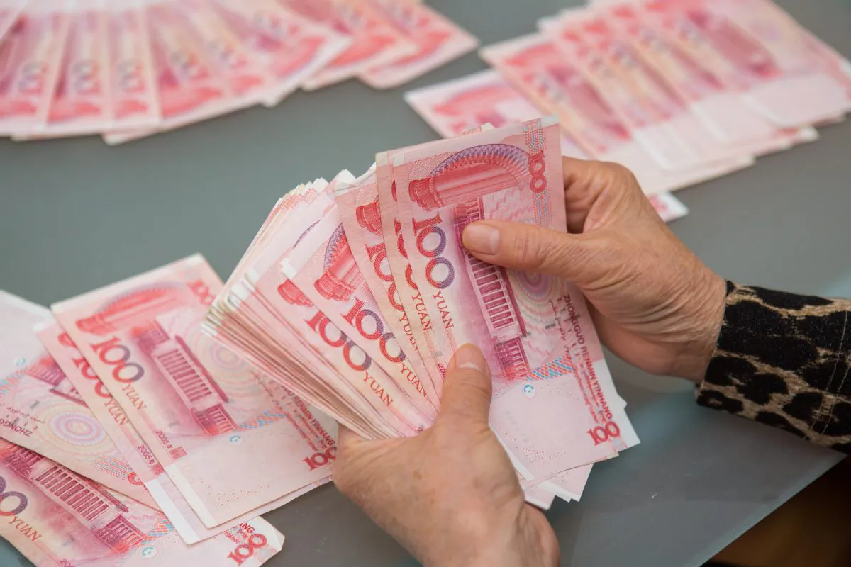 A woman counts Chinese yuan bills worth thousands of dollars in Vancouver, Canada on Oct. 27, 2015. (Benjamin Chasteen/The Epoch Times)