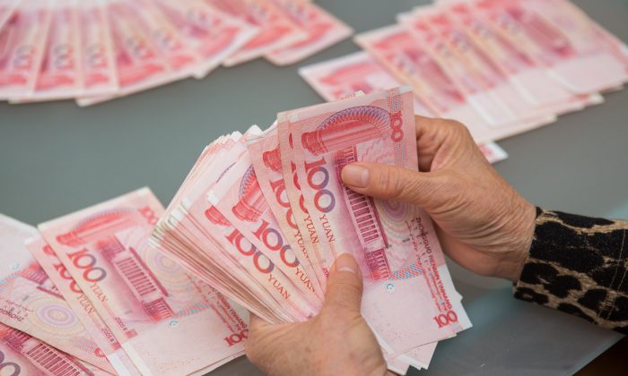 A woman counts Chinese yuan bills worth thousands of dollars in Vancouver, Canada on Oct. 27, 2015. (Benjamin Chasteen/The Epoch Times)