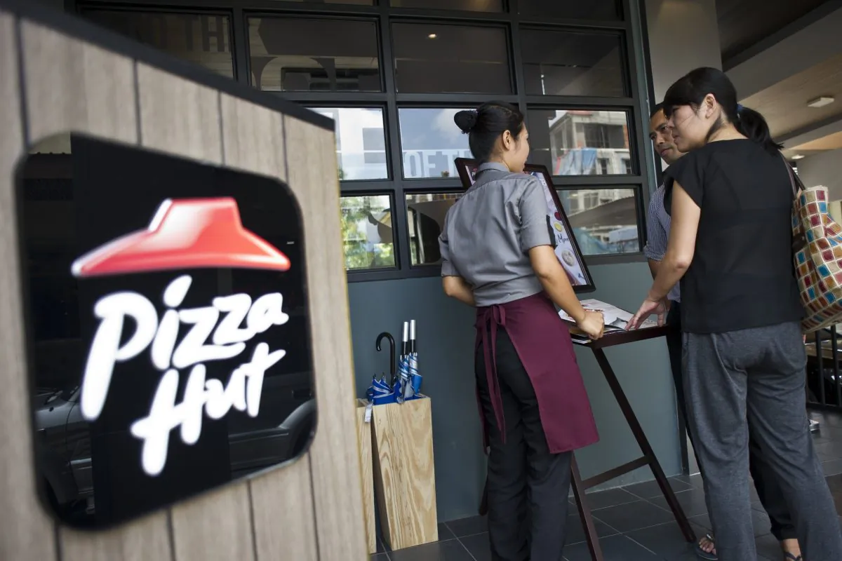 A staff member attends to customers browsing the menu of Pizza Hut's first restaurant in Yangon on October 22, 2015. (Ye Aung Thu/AFP/Getty Images)