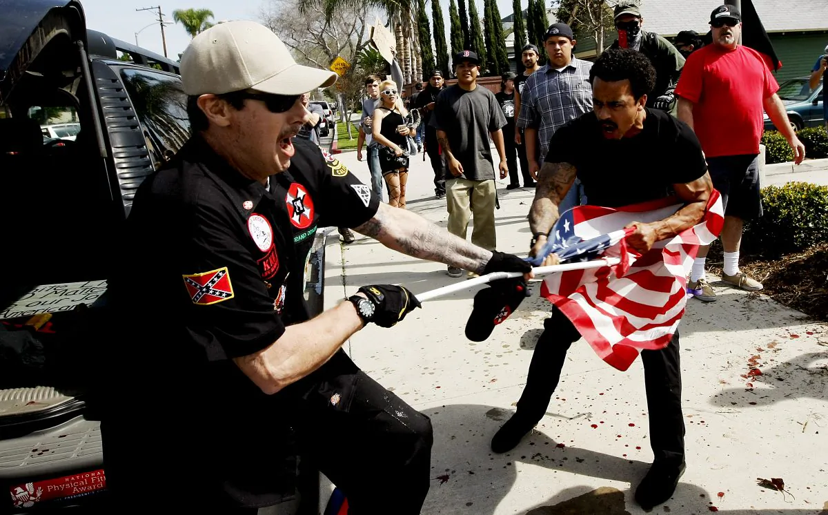 A Ku Klux Klansman (L) fights a counter-protester for an American flag after members of the KKK tried to start a "White Lives Matter" rally at Pearson Park in Anaheim on Feb. 27, 2016. (Luis Sinco/Los Angeles Times via AP)