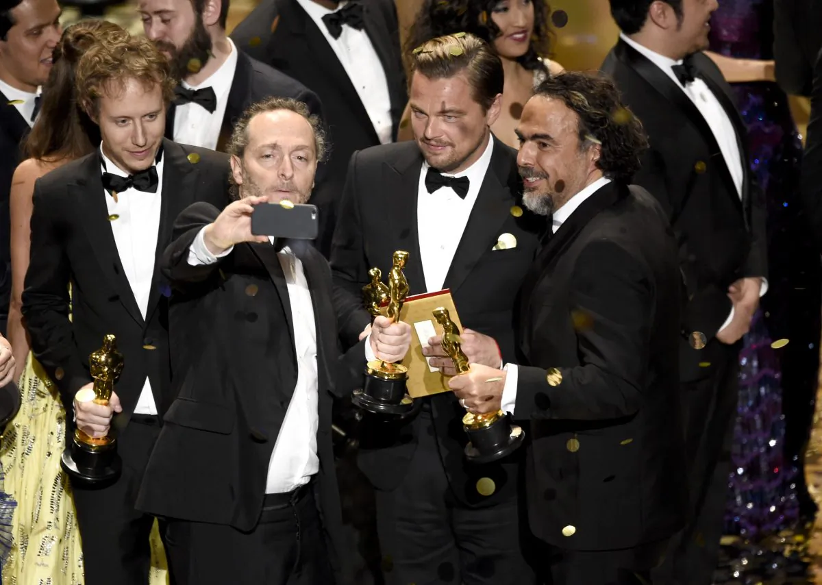 Emmanuel Lubezki, from left, Leonardo DiCaprio, and Alejandro G. Inarritu take a selfie on stage at the conclusion of the show at the Oscars, Feb. 28, 2016, at the Dolby Theatre in Los Angeles. (Chris Pizzello/Invision/AP)